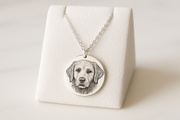 Engraved Pet Face Necklace showing a round silver pendant with a detailed engraved dog portrait on a display stand