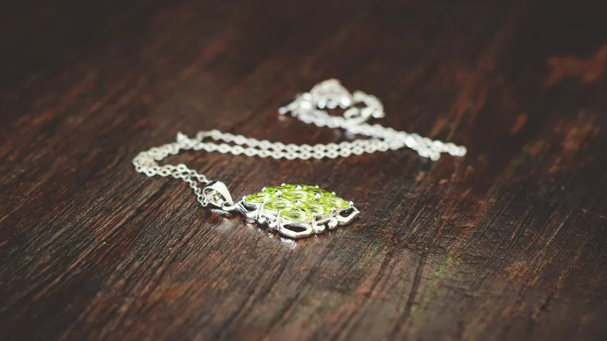 Silver pet face necklace with green stones on wooden surface Real Stories of Love and Loss Behind Pet Face Necklaces