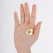 Hand holding gold Pet Heart Keychain engraved with cat face and personalized name Josh on white background