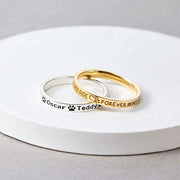 Custom Pet Name Ring set showing silver and gold engraved bands with paw prints and names Oscar and Teddy on white tray